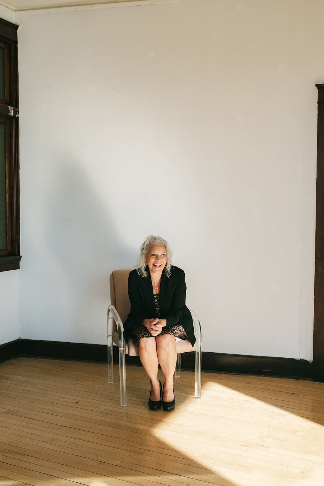 Misty Hughes on overcoming loneliness, know you are not alone as you feel. A bright light shining in the room by her feet and a soft supportive shadow standing behind her as she sits with a smile.